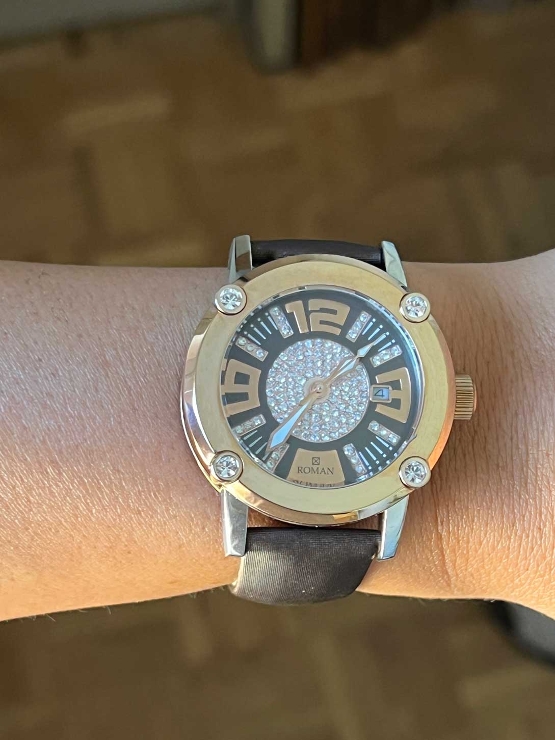 Reloj Román rosa y blanco con correa de seda color marrón.